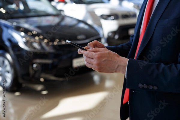 Fototapeta Man using mobile smartphone at dealer showroom.