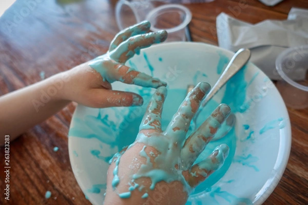 Fototapeta young child with focus on slime covered hands  