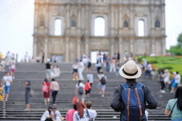 Fototapeta Young man traveling backpacker with hat, Asian hipster traveler looking to Ruins of St. Paul's, Historic Centre of Macau, a UNESCO World Heritage Site. landmark and popular for tourist attractions