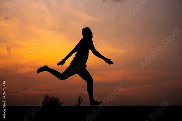 Fototapeta Man running alone at beautiful sunset in the road at park . Summer sport and freedom concept. Athlete training on dusk. - Image