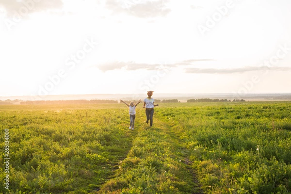 Fototapeta Family, summer and holiday concept - little daughter and mother run in the summer field