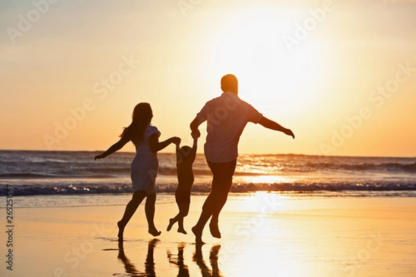 Fototapeta Happy family black silhouette on sun background. Father, mother, baby son run. Child jump with fun by water pool along sea surf on beach. Travel lifestyle, parents walking with kid on summer vacation.