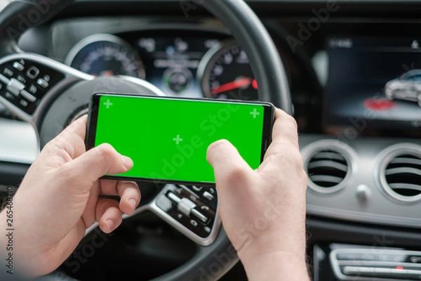 Fototapeta Man using smartphone on the background of a luxury class car dashboard