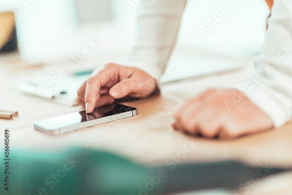 Fototapeta Female carpenter is using mobile phone for text messaging