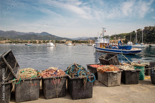 Obraz Scenic view of the harbor of the Bay of Fairy Tales with fishing nets on the dock, anchored boats and the coastline in the background in a sunny spring day, Sestri Levante, Liguria, Italy