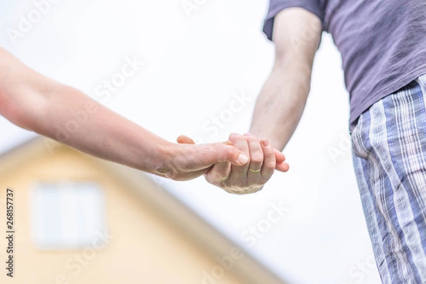 Fototapeta man's and woman's hand on the background of the pediment of the house and sky