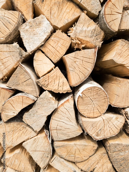 Fototapeta Background of stacked split logs closeup. Wood in the woodpile.