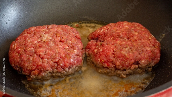 Fototapeta greasy burgers cooking in non stick pan