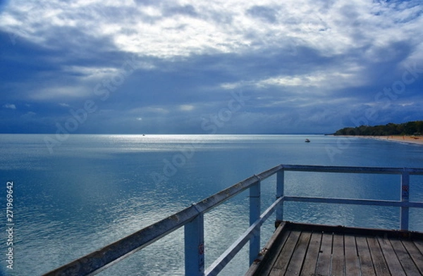 Fototapeta Gushing sea on a cloudy day. Horizontal view of dramatic overcast sky and sea. Fifty shades of blue and gray. View from a wooden pier.