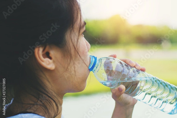 Fototapeta Sporty woman drinking water after her training in the park at the morning.healthy lifestyle concept .