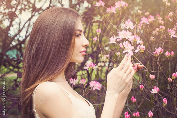 Fototapeta Beautiful woman face with clear skin, profile. Healthy girl sniffing flowers