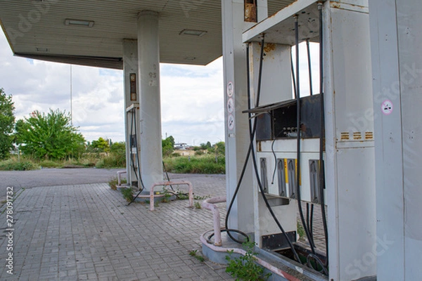 Fototapeta Old abandoned gas station, broken Windows, torn hoses. Problems of migrants in Europe.