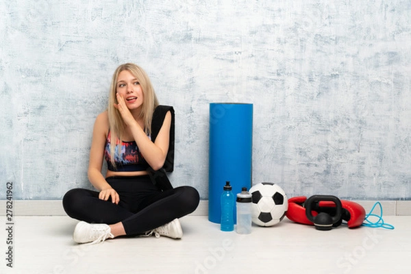 Fototapeta Young blonde sport woman sitting on the floor whispering something