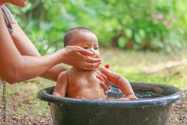 Fototapeta Asian baby in Bathtub  with her mother in the garden.