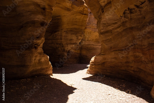 Fototapeta Red canyon desert scenic landscape narrow path way trail between steep sand stone bare rocks, big contrast with lights and shadows and summer Middle East hot season weather time 