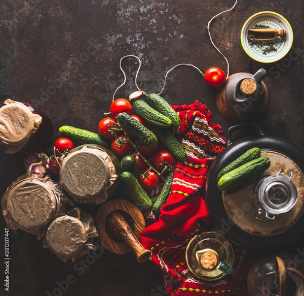 Fototapeta Pickle vegetables preparation on dark rustic background with ingredients,  vinegar bottle , seasoning and jars. Top view. Copy space. Healthy way of harvest storage