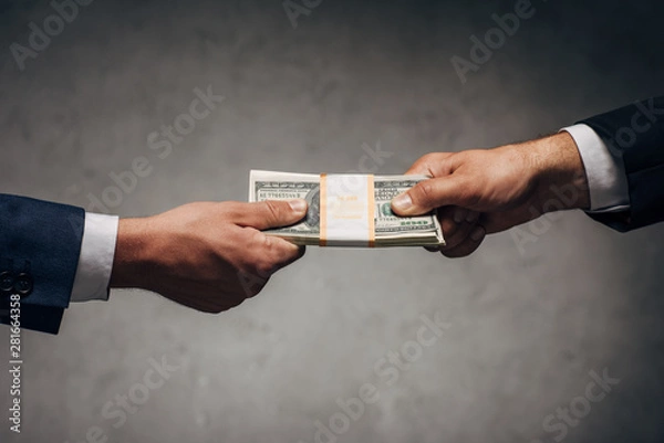 Fototapeta cropped view businessman taking bribe near business partner on grey