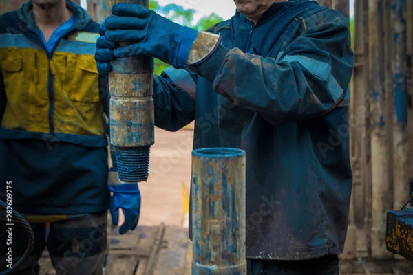 Fototapeta Offshore oil rig worker prepare tool and equipment for perforation oil and gas well at wellhead platform. Making up a drill pipe connection. A view for drill pipe connection from between the stands.