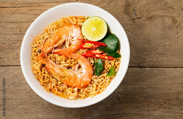 Fototapeta Instant noodles, spicy shrimp soup, spicy, spicy, with Thai spices placed on an old wooden table.