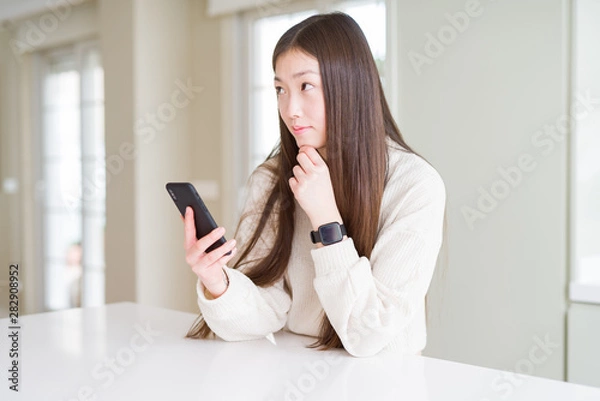 Fototapeta Beautiful Asian woman using smartphone serious face thinking about question, very confused idea