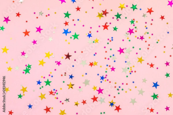 Fototapeta Multi-colored stars glitter on pink background. Festive holiday pastel backdrop. Celebration concept. Top view, flat lay. Horizontal