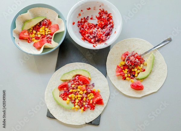 Fototapeta Mexican taco with vegetarian fillings on light table, cooking process