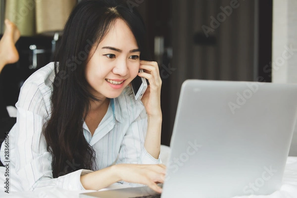 Fototapeta Asian business woman in smile face are using mobile phones and laptops in the office.