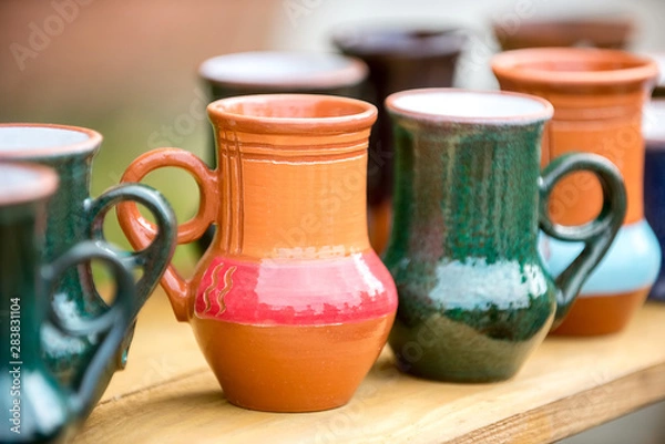 Fototapeta Clay glazed mugs handmade in the window at the seasonal fair masters.