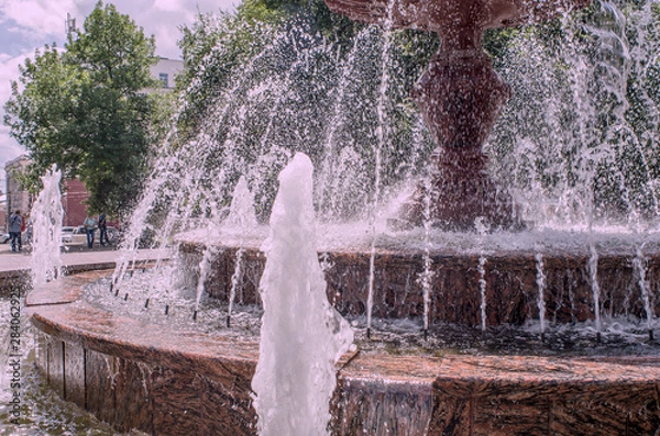 Fototapeta Here is a fragment of a fountain, lined with granite, in the Park in bright sunlight – urban recreation area, close-up, instagram.