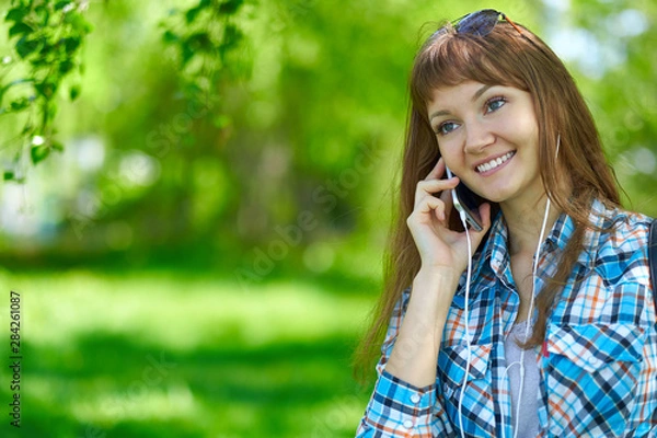 Fototapeta woman talking on phone in summer park.