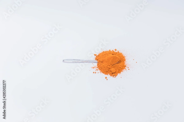 Fototapeta Curry powder in the spoon isolated on white background