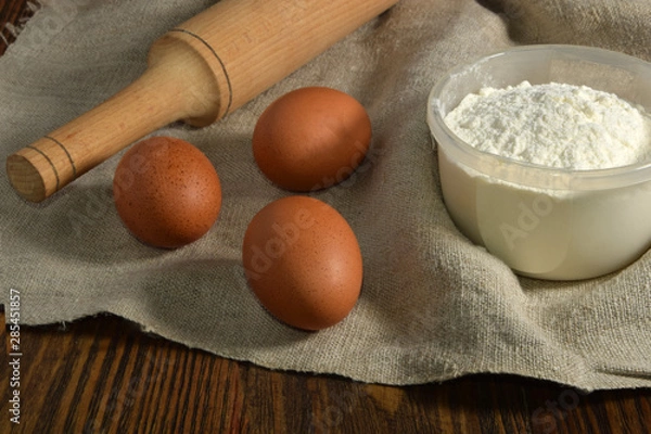 Fototapeta Eggs, rocking chair, flour lying on a linen surface.