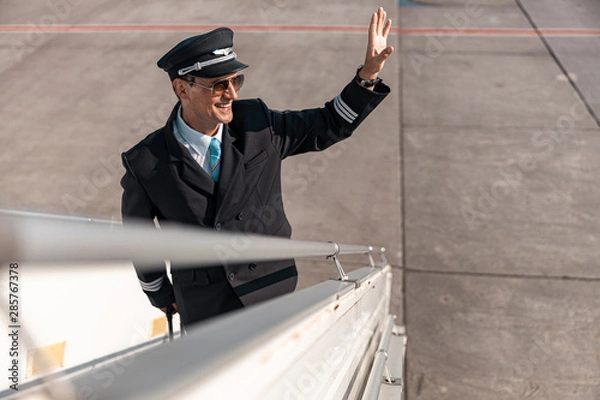 Fototapeta Caucasian happy man in sunglasses smiling to somebody in airport