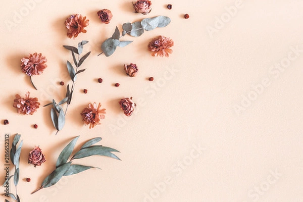 Fototapeta Autumn composition. Pattern made of dried flowers, eucalyptus leaves, berries on beige background. Autumn, fall, thanksgiving day concept. Flat lay, top view, copy space