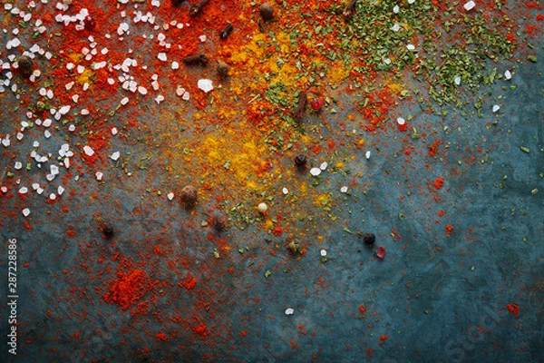 Fototapeta Different spices scattered on the table, red paprika powder, turmeric, salt, cloves, pepper