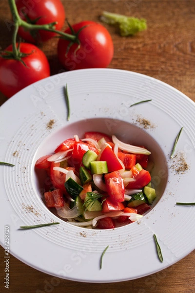 Fototapeta Healthy vegetable salad of fresh tomatoes, cucumbers, bell pepper, onions and herbs. Diet menu