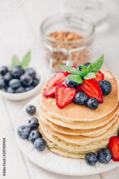 Fototapeta Classic american pancakes with fresh berry on white wood background. Summer homemade breakfast.