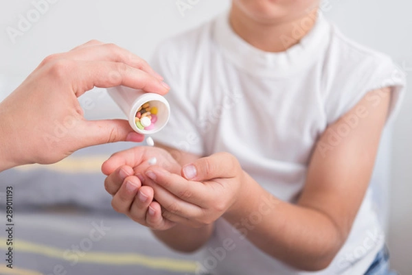 Fototapeta Doctor prescribes pills for a little boy. Treating a child at home