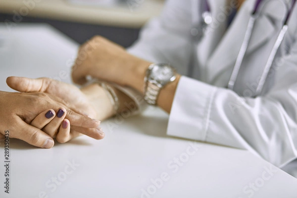 Fototapeta Woman doctor calms patient and holds hand