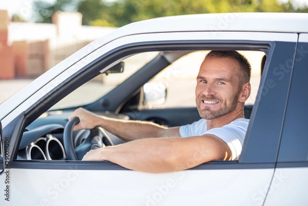 Fototapeta Attractive young man driving a white car.