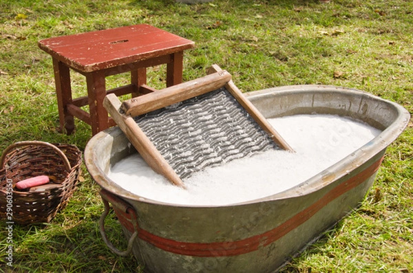 Fototapeta An old fashioned washing trougth filled with water, a vintage washboard and soap that wash the laundry