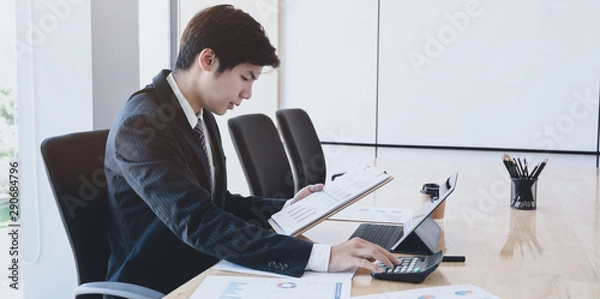 Fototapeta Male accountant analysing and reviewing expenditures for his company