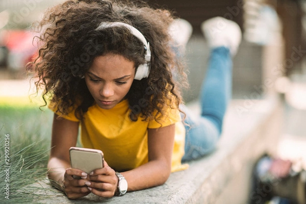 Fototapeta Young woman using phone and listening music 