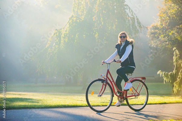 Fototapeta Urban biking - woman riding bike in city park