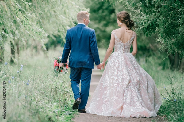 Fototapeta Beautiful wedding couple walking along road at nature