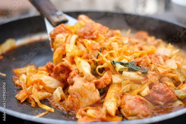 Fototapeta Close up fried Korean food called “Dakgalbi”with spade of frying pan,it's Korean style Chicken with spicy plate.The Korean favorite food which is chicken stir with spicy sauce,vegetable in big hot pan