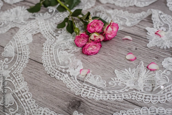 Fototapeta White wooden background with white spring flowers roses and lace ribbon. Happy womans day. The texture of lace on wooden background.