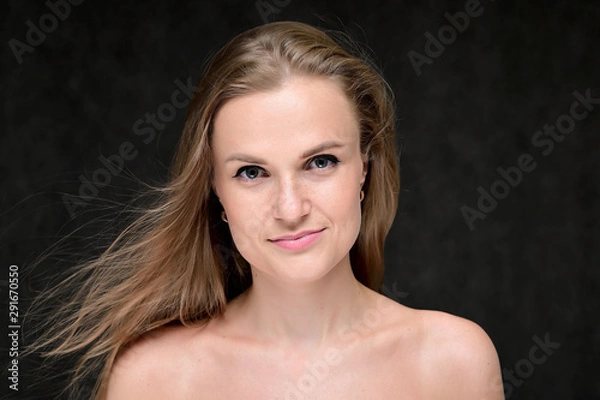 Fototapeta Close-up portrait of a beautiful girl with long hair and excellent skin on a gray background.