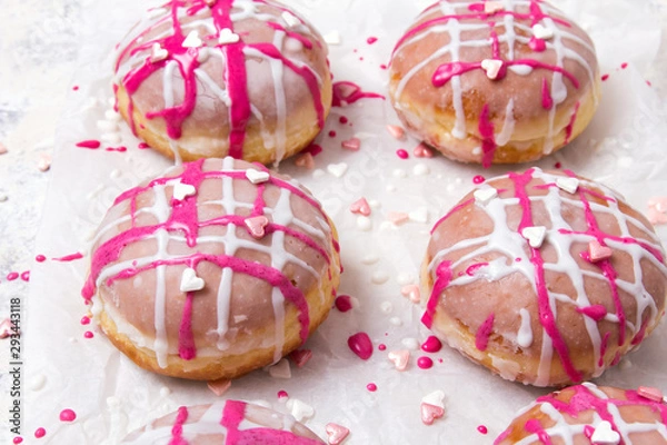 Obraz Traditional Polish donuts with pink frosting and heart sprinkles on light background. Tasty doughnuts with jam.