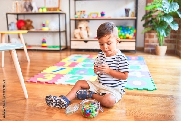 Fototapeta Beautiful toddler boy drinking glass of water at kindergarten